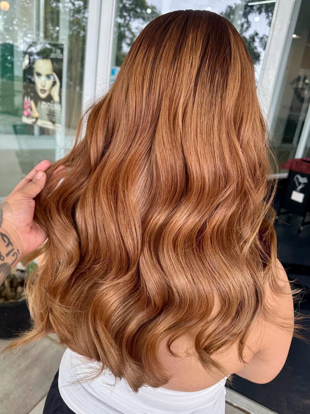 Long, glossy copper balayage waves finished at SandreaLee Salon